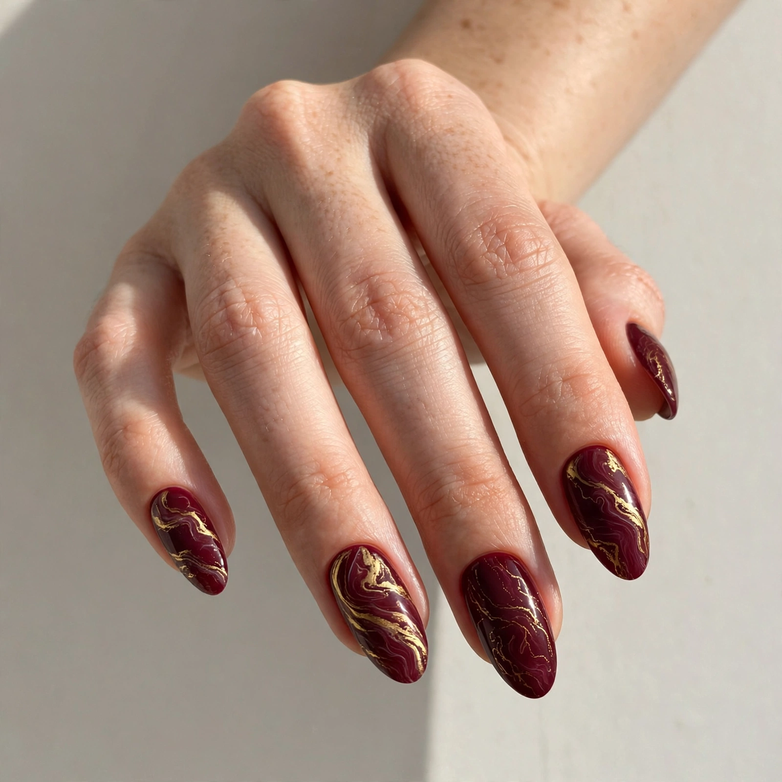 Burgundy nails with gold marble swirls for Valentine's Day